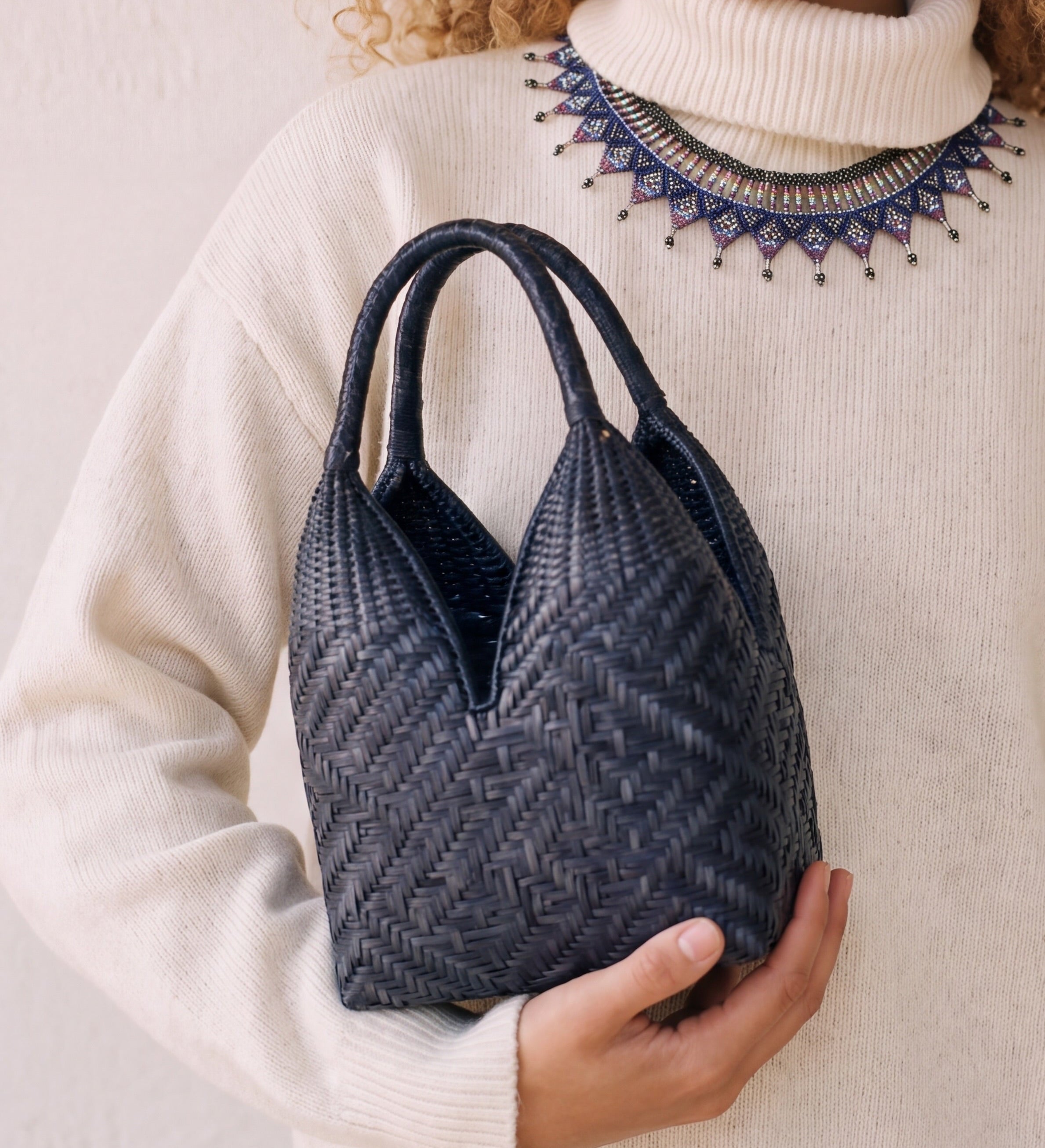 Canastos Indigo handwoven Colombian basket bag, carried with a cream sweater