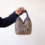 Canastos Tradicional handwoven Colombian basket bag, warm off-white with a blue geometric weave, held in hand