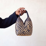 Canastos Tradicional handwoven Colombian basket bag, warm off-white with a blue geometric weave, held in hand