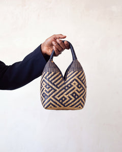 Canastos Tradicional handwoven Colombian basket bag, warm off-white with a blue geometric weave, held in hand