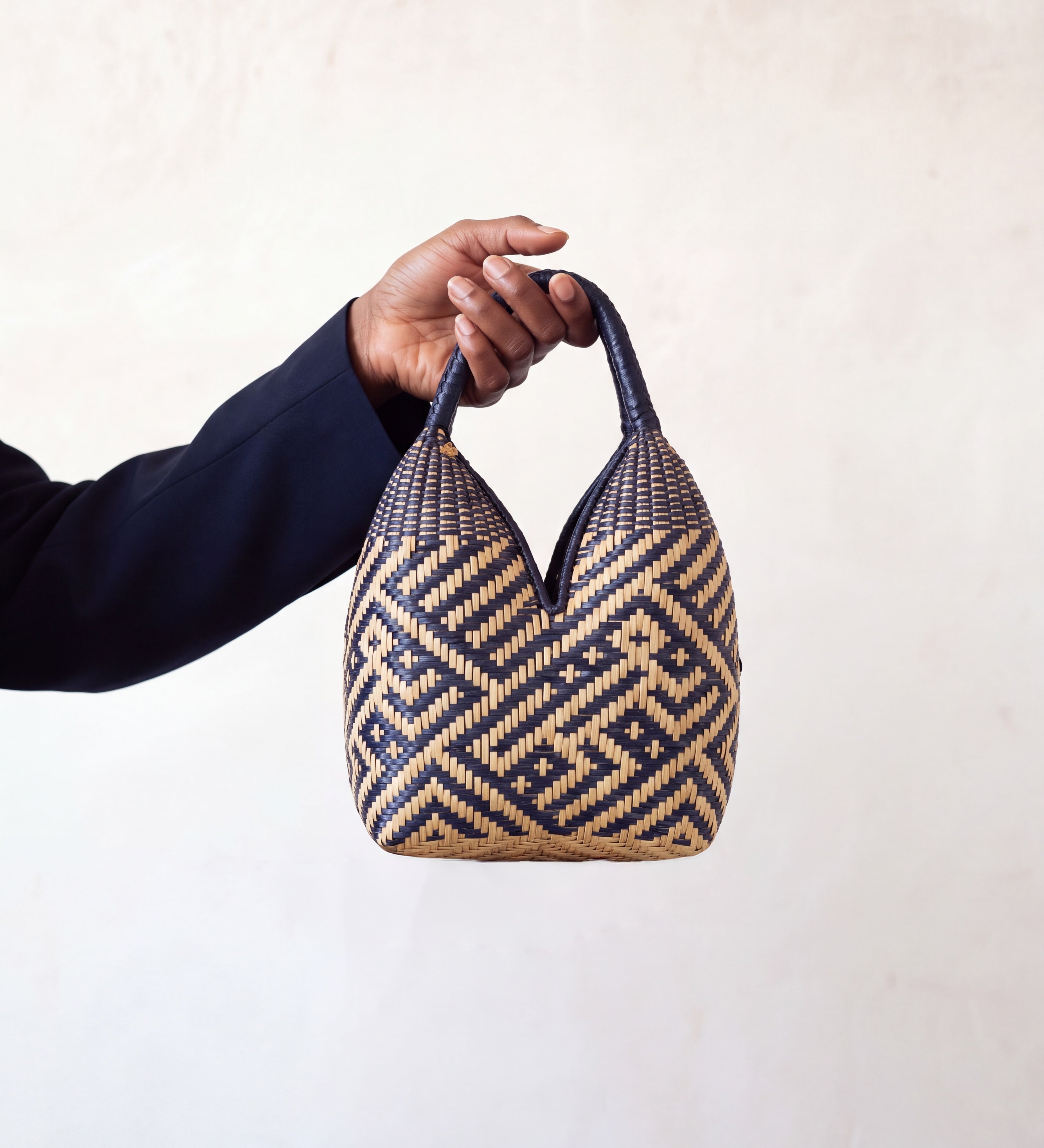Canastos Tradicional handwoven Colombian basket bag, warm off-white with a blue geometric weave, held in hand