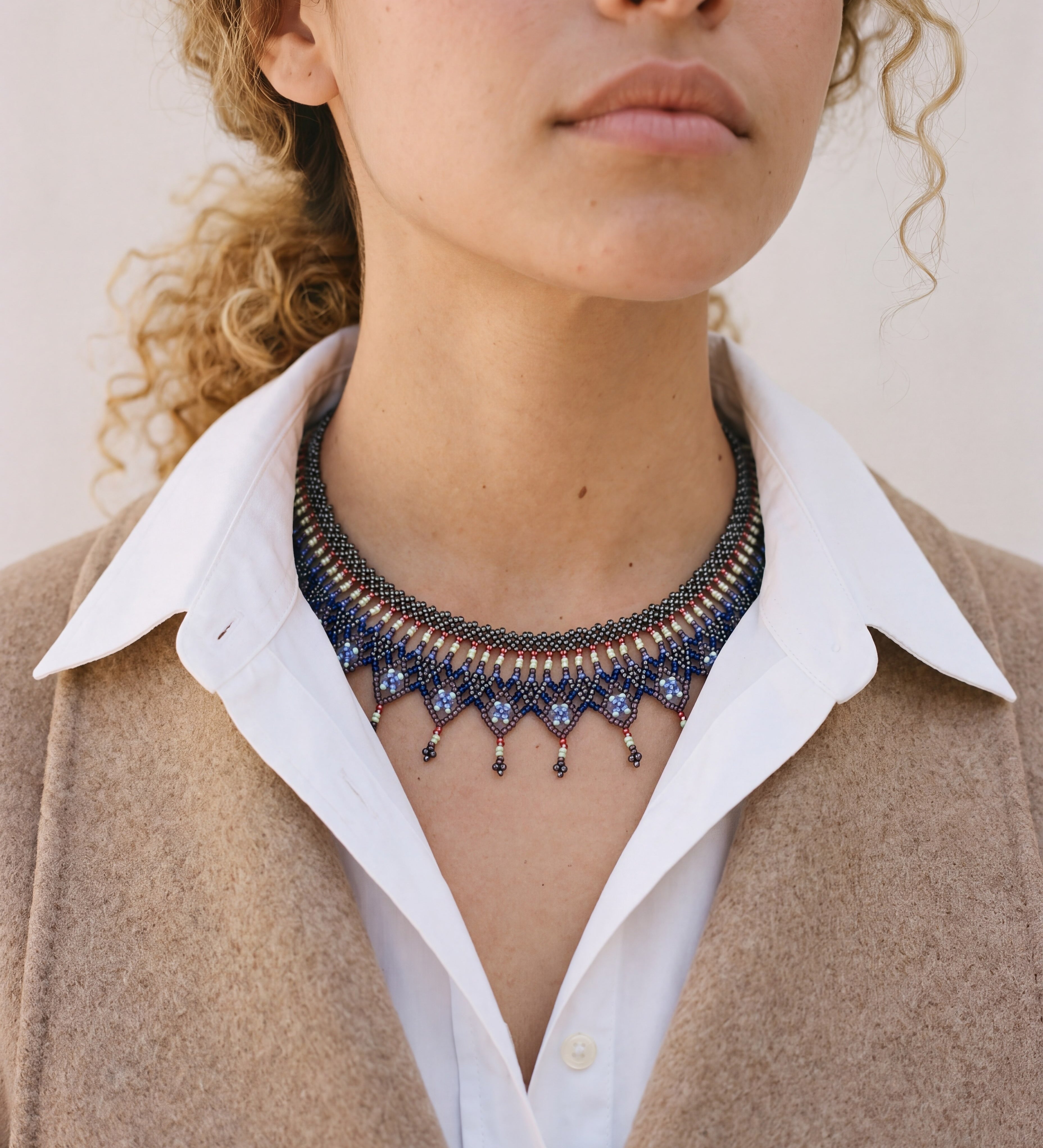 Okamas Vida Azul small beaded necklace in blue and gold, worn with a white collared shirt