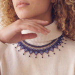 Close-up of the Okamas Vida Azul handmade beaded necklace over a cream turtleneck