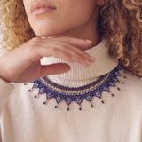 Close-up of the Okamas Vida Azul handmade beaded necklace over a cream turtleneck
