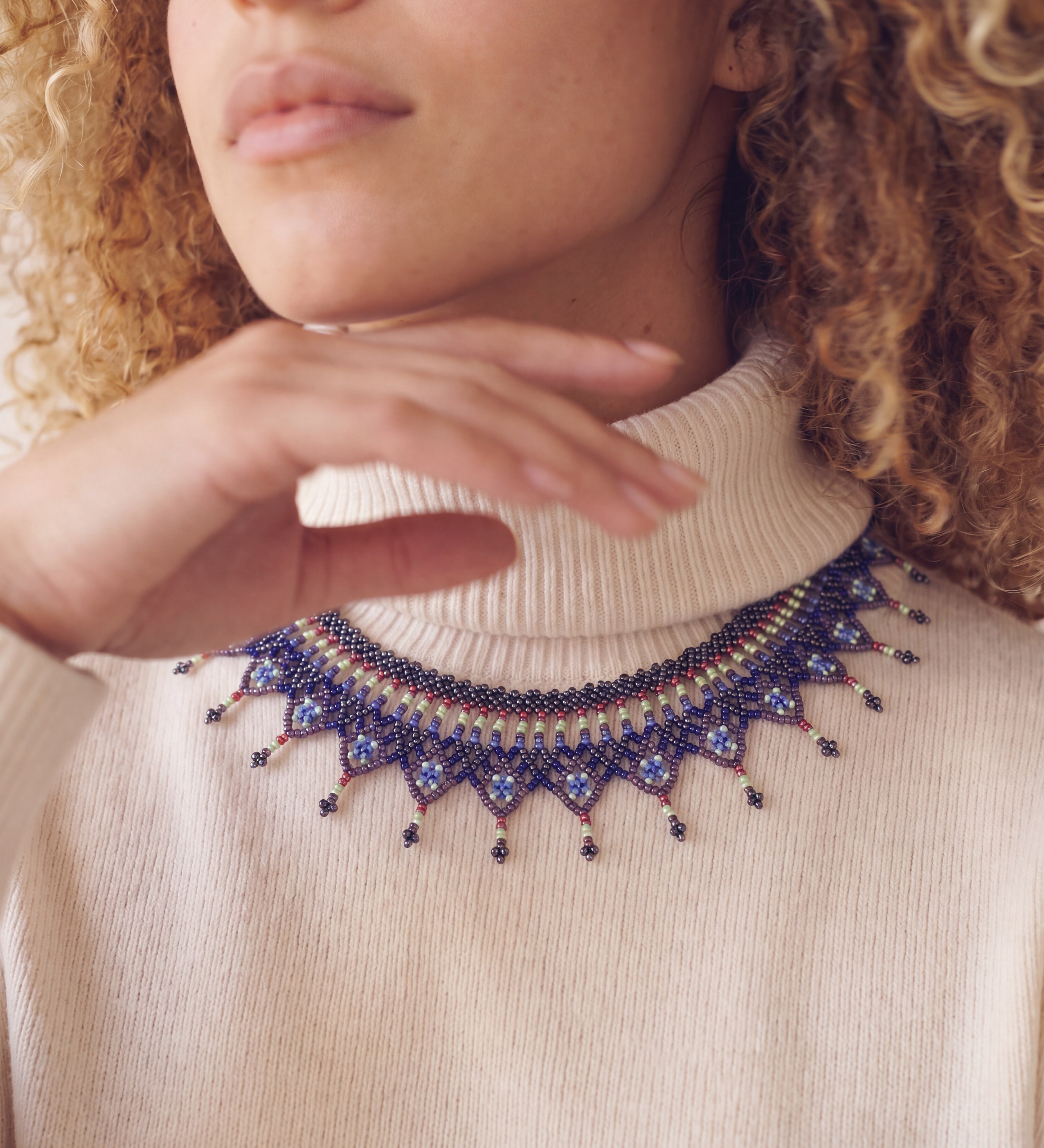 Close-up of the Okamas Vida Azul handmade beaded necklace over a cream turtleneck